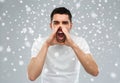 Angry shouting man in t-shirt over snow background