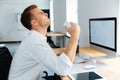 Angry stressed businessman sitting and crumpling paper in office