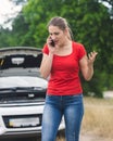 Portrait of angry stressed woman shouting at car assistance service because of broken car Royalty Free Stock Photo