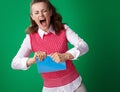 Angry student woman tearing blue notebook on green background