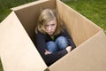 Angry teenage girl sitting in a cardboard box