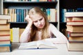 Angry and tired schoolgirl studying with a pile of books Royalty Free Stock Photo