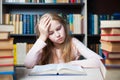 Angry and tired schoolgirl studying with a pile of books Royalty Free Stock Photo