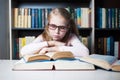 Angry and tired schoolgirl studying with a pile of books Royalty Free Stock Photo