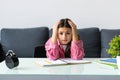 Angry and tired teen schoolgirl studying with a pile of books on her desk Royalty Free Stock Photo