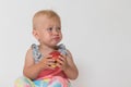 Angry toddler girl is sitting and holding red apple Royalty Free Stock Photo