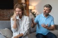 Angry upset mature european husband yells at crying wife, couple quarreling in living room interior Royalty Free Stock Photo