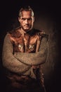 Angry viking in a traditional warrior clothes, posing on a dark background.