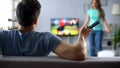 Angry wife quarreling with husband watching football game, conflict in relations