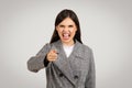 Angry woman in blazer pointing and shouting, frustration evident