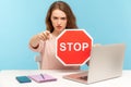 Angry woman boss, office employee at workplace, holding stop symbol and pointing to camera