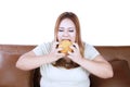 Angry woman eats a hamburger on studio Royalty Free Stock Photo