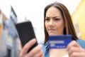 Angry woman paying with credit card and phone outside