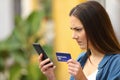 Angry woman paying with credit card and smart phone outdoors