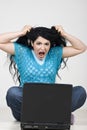 Angry woman pulling out hair in front of laptop