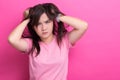 Angry woman screaming out and pulling her hair over pink background Royalty Free Stock Photo