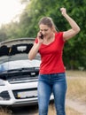 Angry woman shouting in mobile phone because of the broken car o Royalty Free Stock Photo
