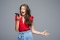 Angry woman shouting on phone standing over gray background Royalty Free Stock Photo