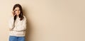 Angry woman shows mouth zipper, seal lips gesture, standing over beige background, taboo sign