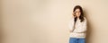 Angry woman shows mouth zipper, seal lips gesture, standing over beige background, taboo sign