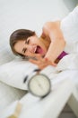 Angry woman stretching to turn off alarm clock