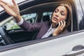 Angry woman using phone pissed off by drivers in front of her and gesturing with hands Royalty Free Stock Photo