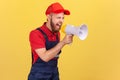 Angry worker man holding megaphone near mouth loudly speaking, screaming, protesting. Royalty Free Stock Photo