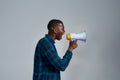 Angry young african american male protester, activist looking away, screaming using megaphone, posing isolated over gray Royalty Free Stock Photo