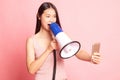 Angry young Asian woman shout with megaphone to mobile phone Royalty Free Stock Photo