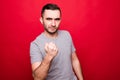 Angry young Caucasian man show clenched fist threaten or give warning isolated on red studio background demonstrate threat or Royalty Free Stock Photo