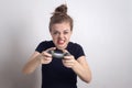 Angry young Caucasian woman girl holding joystick game pad controller, playing computer game.