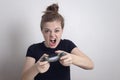 Angry young Caucasian woman girl holding joystick game pad controller, playing computer game.