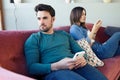 Angry young couple ignoring each other using phone after an argument while sitting on sofa at home Royalty Free Stock Photo