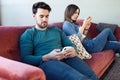 Angry young couple ignoring each other using phone after an argument while sitting on sofa at home Royalty Free Stock Photo