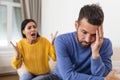 Angry young couple sit on couch in living room having family fight or quarrel suffer from misunderstanding, millennial husband and Royalty Free Stock Photo