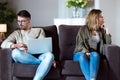Angry young couple sitting on sofa together and looking to opposite sides at home. Royalty Free Stock Photo