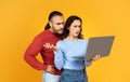 Angry young couple using modern laptop on yellow Royalty Free Stock Photo