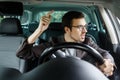 Angry young driver quarrels with other drivers. His left hand is on the steering wheel