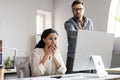 Angry young european man boss scolds to frightened shocked sad manager lady at workplace with computer