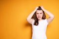 Angry young girl in a white t-shirt pulls her hair out with her hands due to head pain after installing braces