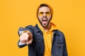 Angry young hipster guy in fashion jeans denim clothes posing isolated on yellow orange background. People lifestyle Royalty Free Stock Photo