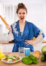 Angry woman screaming and waving rolling pin in home kitchen Royalty Free Stock Photo