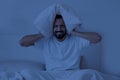 Angry Young Indian Man Covering Ears With Pillow While Sitting In Bed Royalty Free Stock Photo