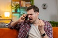 Angry young man arguing talking loudly shouting on smartphone quarrel sitting on couch at home Royalty Free Stock Photo