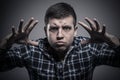 Angry young man in checked shirt threatening us with hands and frightening gaze Royalty Free Stock Photo