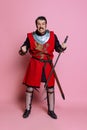 One young man, medieval warrior or knight wearing wearing armor clothing posing isolated over pink background Royalty Free Stock Photo