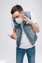 Angry young man in respiratory mask shouting to someone in his smartphone. Royalty Free Stock Photo