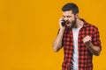 Angry young man screaming on the cell phone isolated on a yellow background Royalty Free Stock Photo