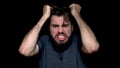 Angry young man shouting, expressing negative emotions, tearing his hair out, isolated on black background. Close up of Royalty Free Stock Photo