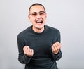 Angry young man shouting with open mouth and very anger face, showing the fists in fashion glasses Royalty Free Stock Photo